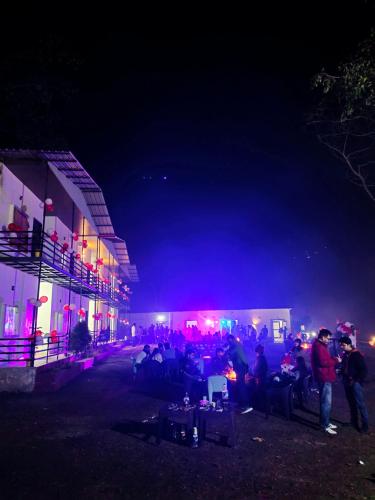 un grupo de personas sentadas fuera de un edificio por la noche en Chill stops Rishikesh titos, en Bijni