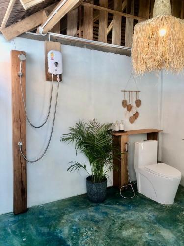 a bathroom with a toilet and a plant in it at The Tropical Koh Mook in Koh Mook