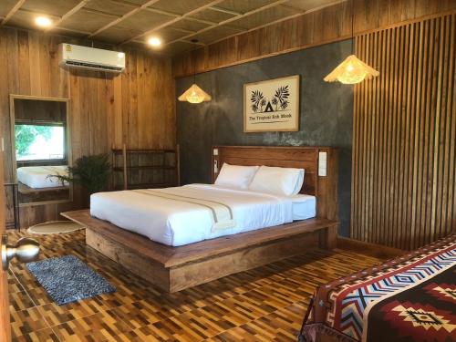 a bedroom with a bed in a room with wooden walls at The Tropical Koh Mook in Koh Mook