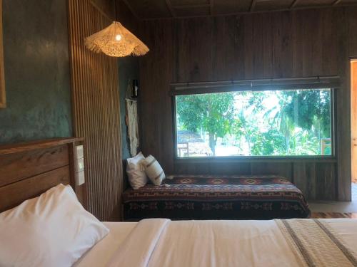 a bedroom with a window with a bed and a bench at The Tropical Koh Mook in Koh Mook
