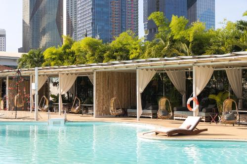 a hotel swimming pool with a laptop on a chaise lounge at Treellion Jungloo in Phnom Penh