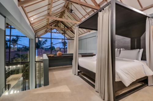 a bedroom with a canopy bed and a balcony at Loft My Seseh by BaliSuperHost in Canggu