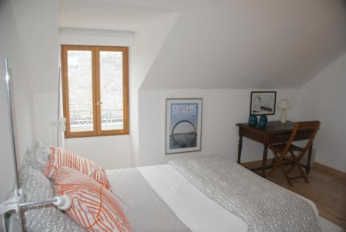 a bedroom with a bed and a desk and a window at La Vigie in Couëron