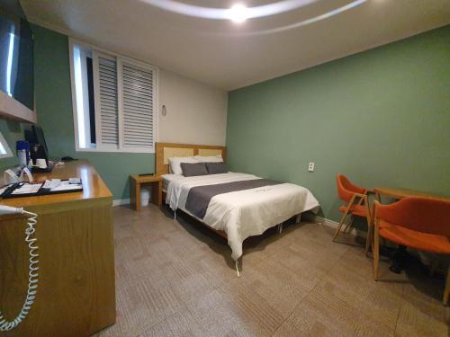 ポハンにあるThe 7 Hotelのベッドルーム1室(ベッド1台、テーブル、デスク付)