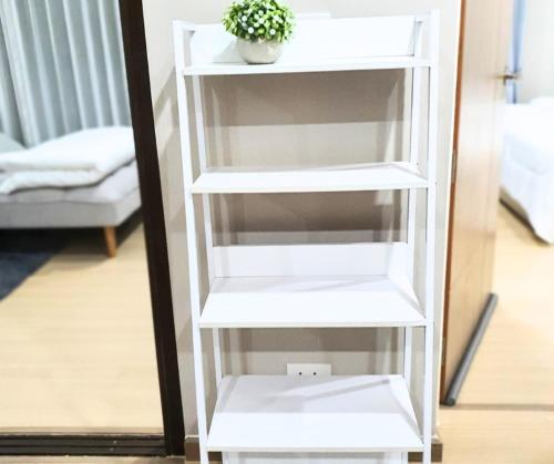 a white book shelf with a plant on it at Family Condo-style in Phra Nakhon Si Ayutthaya