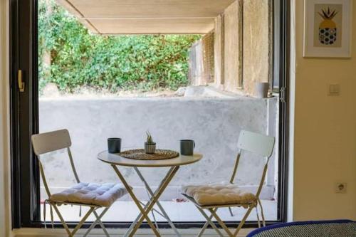 einen Tisch und zwei Stühle vor einem Fenster in der Unterkunft Studio Krinon - Paleo Psychiko in Athen