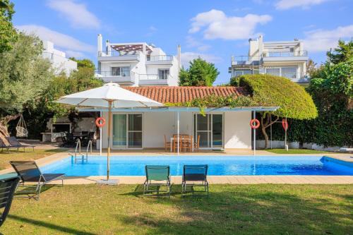 uma casa com uma piscina com cadeiras e um guarda-sol em Lagonisi Beach House em Lagonissi