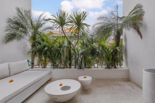 a white room with a toilet and palm trees at Loft My Seseh by BaliSuperHost in Canggu