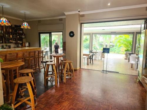 un bar con taburetes de madera y mesas en un restaurante en Mijn Kitchen Coffee Shop and B&B en Blantyre
