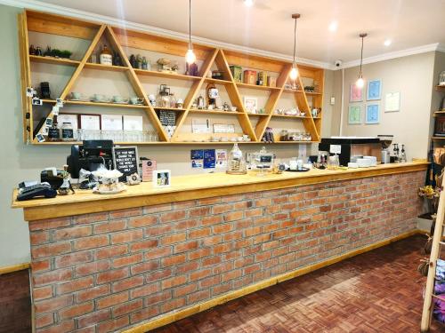 a bar with a brick wall and shelves at Mijn Kitchen Coffee Shop and B&B in Blantyre