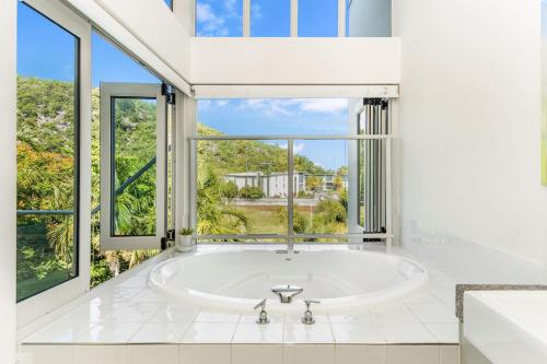 a bath tub in a bathroom with a large window at Beachside Apartment 13 in Nelly Bay