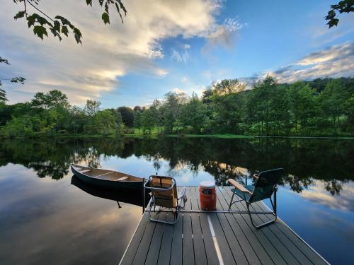 ein Boot und zwei Stühle auf einem Dock auf einem See in der Unterkunft 13-Acre Private Estate, Private Lake, Private Golf Range, Private Forest & Hiking Trails 