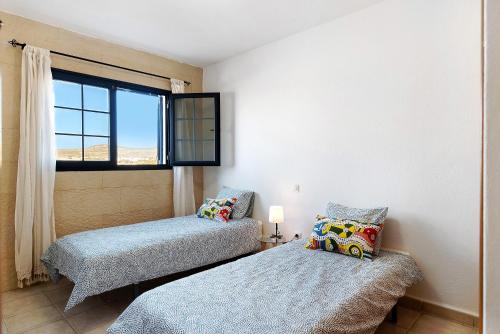 two beds in a room with a window at Apartamento Cabo in Caleta de Sebo