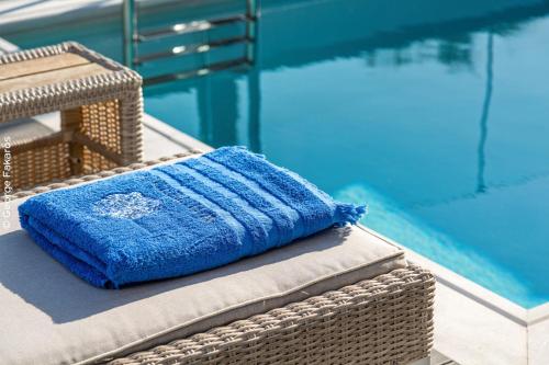 a blue towel sitting on a wicker chair next to a swimming pool at WHITE ROCK VILLAS LEFKADA in Lygia
