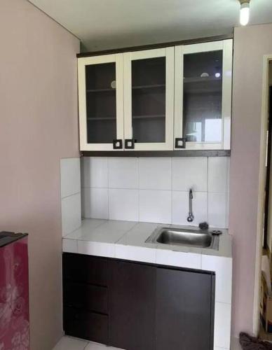uma pequena cozinha com um lavatório e armários em Apartemen Ayodhya 2BR Tower Jade em Tjikokol
