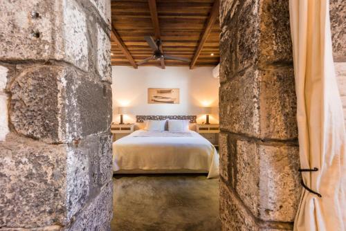 ein Schlafzimmer mit einem Bett und einer Steinmauer in der Unterkunft Quaint 4-bedroom Beach Villa in a fishing village in Grand-Gaube