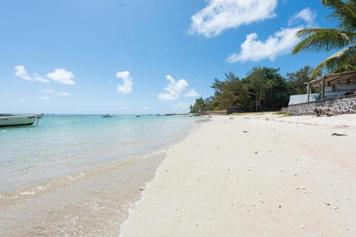 a beach with a boat in the water at Quaint 4-bedroom Beach Villa in a fishing village in Grand Gaube