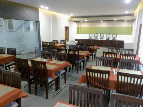 una sala da pranzo con tavoli e sedie in legno di HOTEL THE SENTOSA a Rajkot