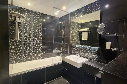 杜拜的住宿－DAMAC Voleo In Business Bay，一间带水槽、浴缸和镜子的浴室