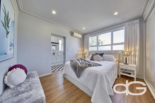 a white bedroom with a large bed and a window at Federal Apartments South Fremantle in South Fremantle