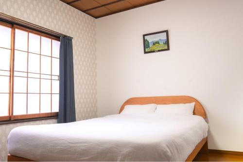 a bedroom with a white bed and a window at White Lodge Fukujuso in Iiyama