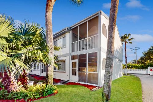 a white house with palm trees in front of it at Sparks & Sunshine in Cape Canaveral