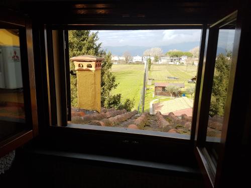 a window with a view of a field and a tower at La Mansarda di Didi in Capannori