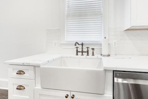 a white kitchen with a sink and a window at Historic Culpeper Farmhouse in Culpeper