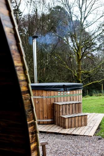 a wooden deck with a hot tub in a field at Tempo Manor Cabins in Tempo