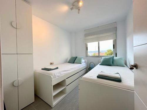 two beds in a white room with a window at Zarauz sea views. Águilas Costa Cálida. in Águilas