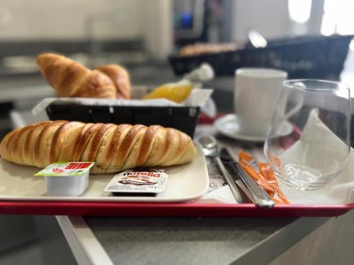 uma bandeja vermelha com um prato de pão e croissants em Armor Hotel em Compiègne