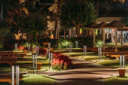 a park with benches and umbrellas at night at Club Tuana Fethiye - All Inclusive in Fethiye