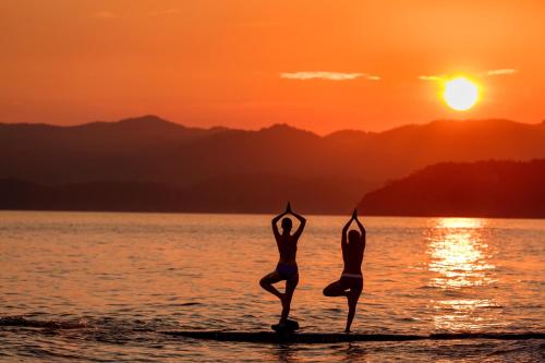 two people doing yoga on the beach at sunset at Club Tuana Fethiye - All Inclusive in Fethiye