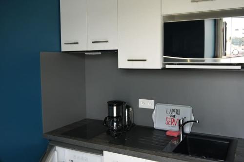 un comptoir de cuisine avec un évier et un micro-ondes dans l'établissement APPARTEMENT EN PLEIN FRONT DE MER : HOUAT, à La Bernerie-en-Retz