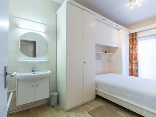 uma pequena casa de banho branca com um lavatório e um espelho. em Sun Beach 2 bedrooms on floor 0 em Middelkerke