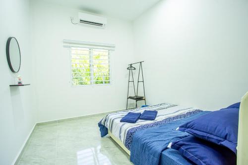 - une chambre blanche avec un lit et des oreillers bleus dans l'établissement De Sungai Langkawi Guesthouse, à Pantai Cenang
