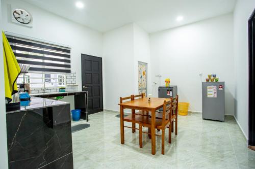 Il comprend une cuisine équipée d'une table en bois et d'un réfrigérateur. dans l'établissement De Sungai Langkawi Guesthouse, à Pantai Cenang