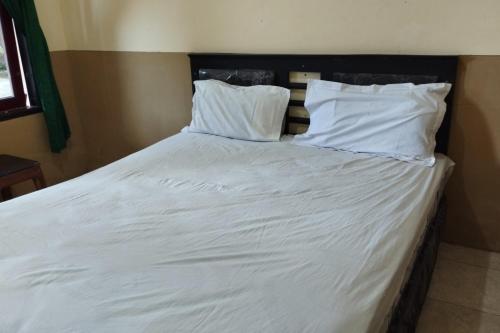 - un lit avec des draps et des oreillers blancs dans l'établissement OYO 93657 Puri Batu Bolong, à Senggigi