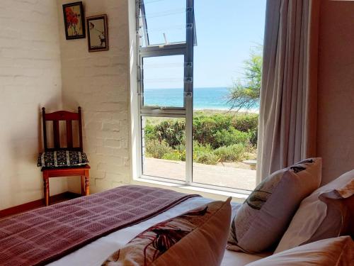 a bedroom with a window with a view of the ocean at Beach Haven Cottage in Britannia Bay