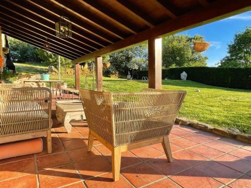 2 Stühle auf einer Terrasse unter einer Veranda in der Unterkunft Habitaciones con baño individual en Casa de campo. Piscina. in Amoeiro