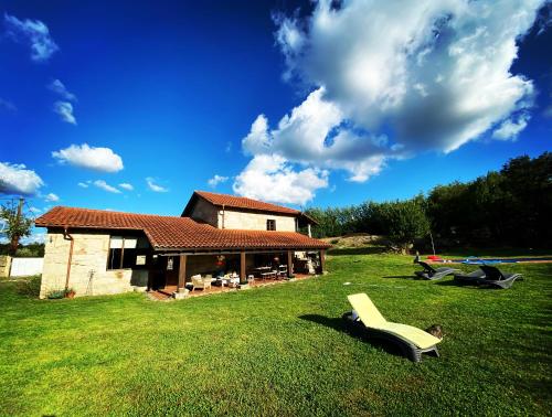a house on a grass field with a yellow chair at Habitaciones con baño individual en Casa de campo. Piscina. in Amoeiro