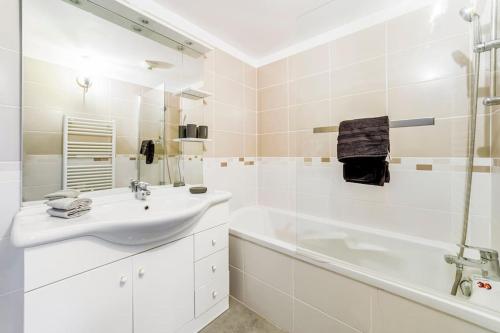 La salle de bains blanche est pourvue d'un lavabo et d'une baignoire. dans l'établissement La Ciotat beau T3, mer, centre, climatisation, parking privé gratuit, à La Ciotat