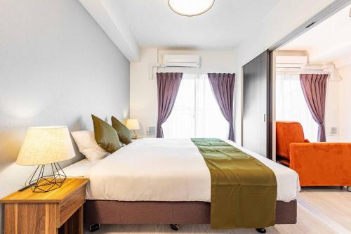 a bedroom with a large bed and a chair at FDS Plaisir in Osaka
