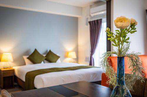 une chambre d'hôtel avec un lit et un vase avec une rose dans l'établissement FDS Plaisir, à Osaka