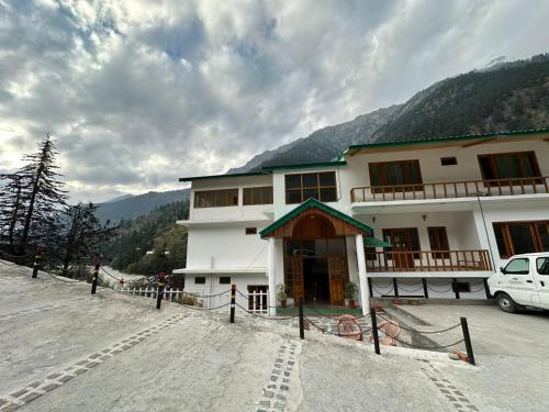 a large building with a car parked in front of it at Prakriti-The Retreat in Gangotri