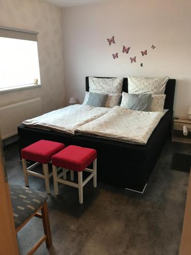 a bedroom with a large bed with two red seats at Ferienwohnung Nordmoor in Blomberg