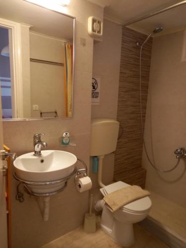 een badkamer met een wastafel, een toilet en een spiegel bij Evie's apartment in Kalamata