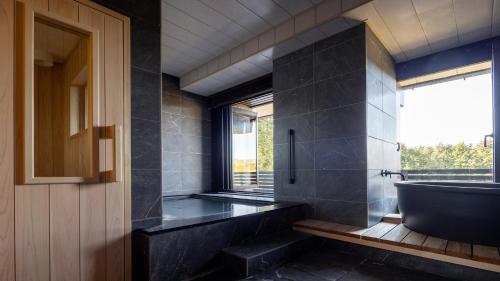 a bathroom with a bath tub and a window at Sengokubara COCON in Hakone