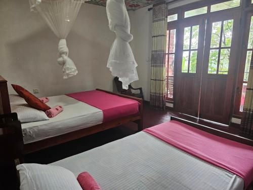 dwa łóżka w pokoju z różową pościelą i oknami w obiekcie Opal Cottage Ella w mieście Ella