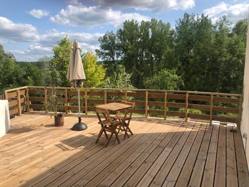 eine Holzterrasse mit Tisch und Sonnenschirm in der Unterkunft Logis Hôtels Troglododo in Azay-le-Rideau